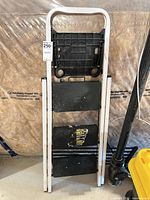 Ladder folded showing three black steps and tool tray