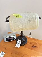 Lamp and clock on wooden surface; lamp shade detail with size note