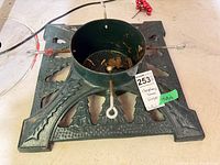 Oblique view of the cast iron tree stand showing base design, central cup, and hardware