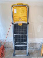 Folded Cosco 3-step ladder standing upright