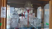Group view showing two covered candy jars, four red-stem goblets, square lidded box