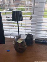 Table lamp, glass wax warmer/vase, and metal lantern on desk