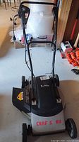 Front view of Craftsman corded mower showing deck, branding remnants, motor cover label, handle, side discharge chute