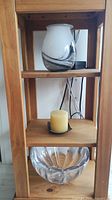Swirl glass vase on shelf, pillar candle on metal dish, clear bowl below