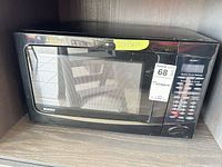 Front view of black Kenmore countertop microwave in shelving unit