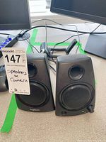 Front view of both Logitech speakers with lot tag visible