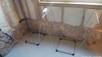 Two metal folding garbage bag holders standing side by side