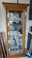 Front close view of oak curio cabinet showing glass door, shelves and mirrored back