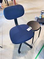 Full view of blue fabric office chair beside black stool