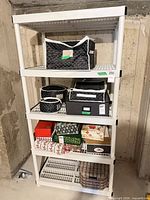 Full view of white plastic shelving unit with items on shelves