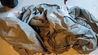 Overall view of folded gray polyester car cover with label visible