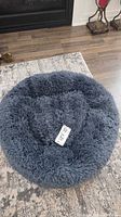 Top view of dark gray round shag dog bed with measurement tag
