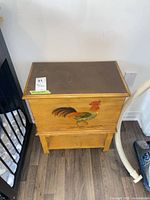 Front and top view of wooden chest showing rooster motif and lower shelf