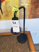 Full view of black metal lamp with smoked glass globe and height tag
