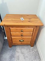 Front view of solid pine nightstand with three drawers and brass hardware
