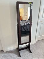 Front view of freestanding Songmics jewelry armoire showing full-length mirror and dark brown finish