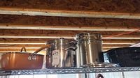 Left to right: copper nonstick pot with lid, stainless stock pot with insert and lid, black speckled enamel pot with lid
