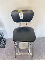 Front view of stool showing seat, backrest, frame and footrest