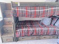 Full view of bunk bed showing staircase, guardrail, bedding, under-bed drawers