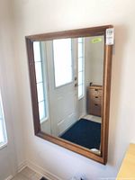 Full view of rectangular wood wall mirror hung vertically