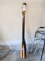 Both wooden paddles leaning against wall showing full length and blade designs