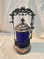 Full view of cobalt glass jar in ornate silverplate stand with lid