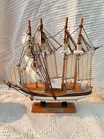 Front view of wooden three-masted model ship on stand