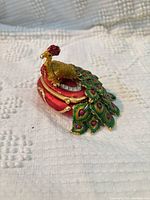 Peacock trinket box closed, side view shows enamel colors and rhinestones