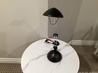 Full view of black metal adjustable desk lamp on table