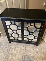 Front view of black cabinet showing two mirrored lattice doors and overall design