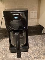 Front view showing Cuisinart logo, clock display, carafe in place
