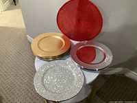 Stack of gold matte plates, two silver glitter plates, two red background plates visible
