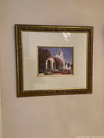 Print of white church with archway in gold frame, matted