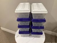 Stack of eight clear bins: four per column, white lids on top, blue bases visible