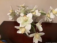 Arrangement of silk orchids in clear vase on wooden surface