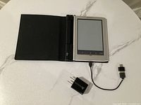 Sony e-reader open in cover with connected USB cable and wall adapter