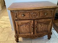 Front view of Stanley walnut nightstand showing drawer, cabinet doors, carvings, and feet