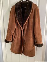Full front view of brown shearling coat on hanger