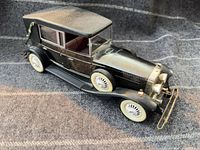 Front three-quarter view showing overall car design, paint, side spare wheel, brass bumper and whitewall tires