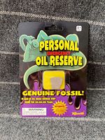 Front view of sealed Toysmith Personal Emergency Oil Reserve blister card with fossil visible