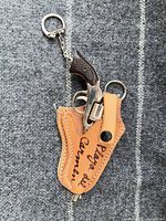 Revolver keychain inside leather holster with ring and chain visible