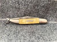 Knife closed showing yellow pearl handle and Fish Cutter shield