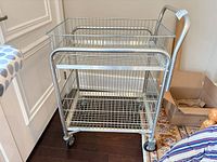 Full view of chrome metal utility cart showing two tiers and casters