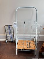 White wire shopping cart beside folded chrome luggage cart