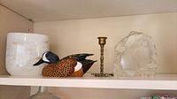 Shelf view showing vase, duck decoy, brass candlestick and crystal owl paperweight