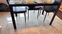 Full view of black glass dining table with chairs and items on top