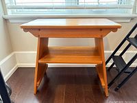 Front view of oak two-tier table showing top, shelf, legs