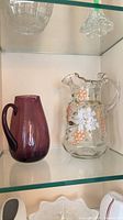 Shelf view showing both the purple vase and clear floral pitcher