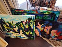 Three canvases showing fronts of all paintings leaning together