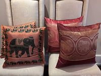 Four embroidered satin pillow covers displayed on chairs